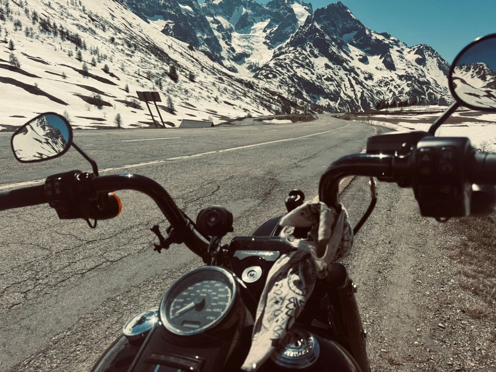 Rider POV from Harley Road King handlebars on a snowy Alpine mountain pass
