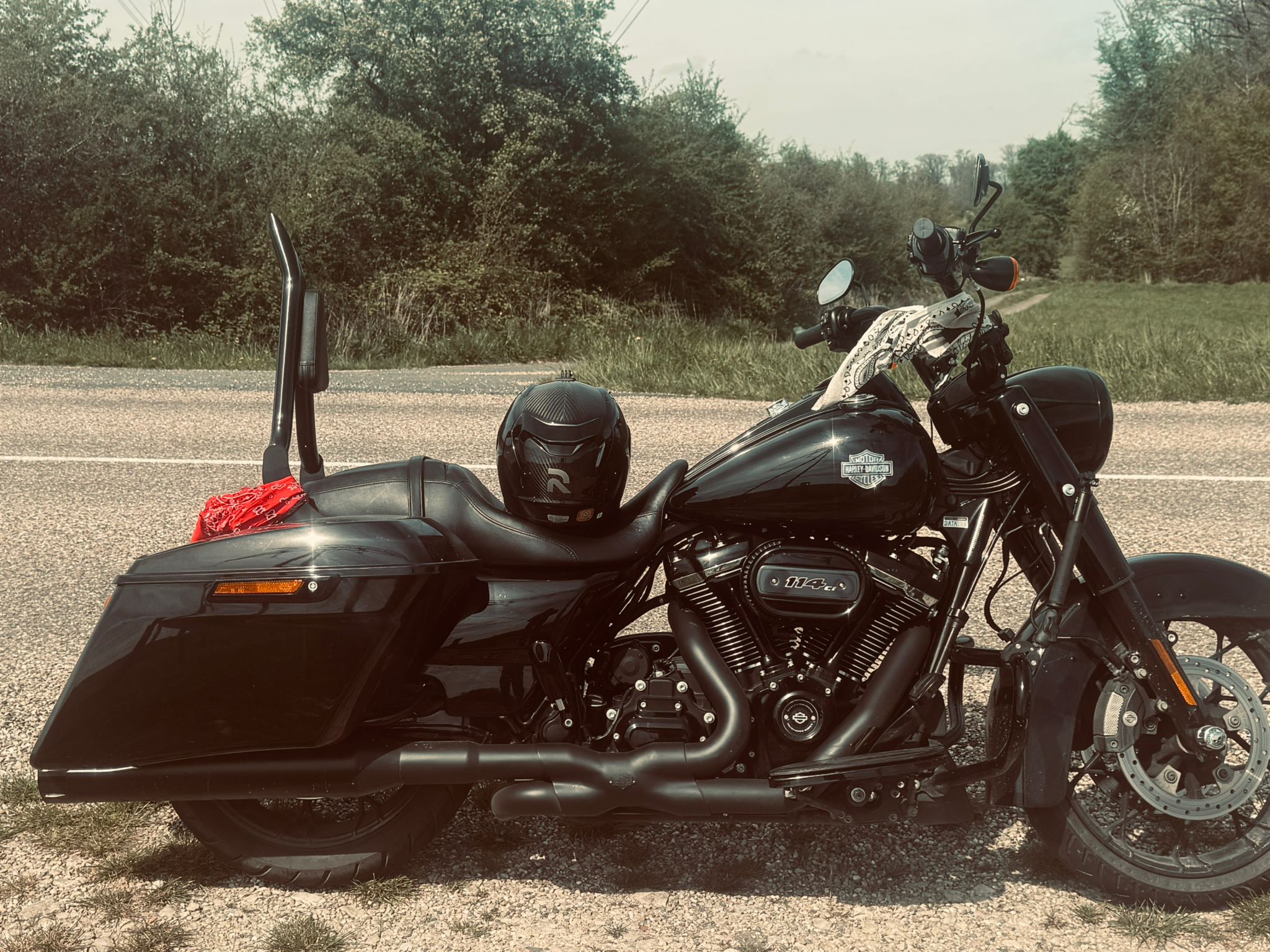 Black Harley Road King Special 114 parked on a country road with helmet on seat and red bandana on pannier
