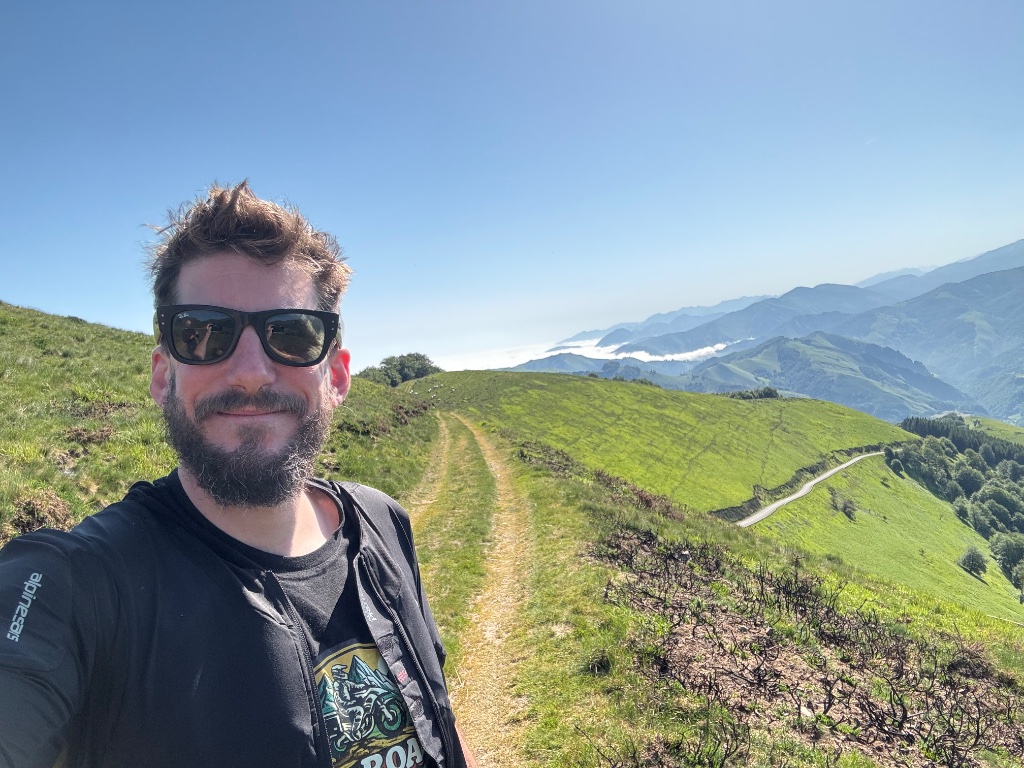 Josh selfie on Pyrenean mountain ridge above cloud inversion — Wild Roads Motorcycle Tours — May 2026