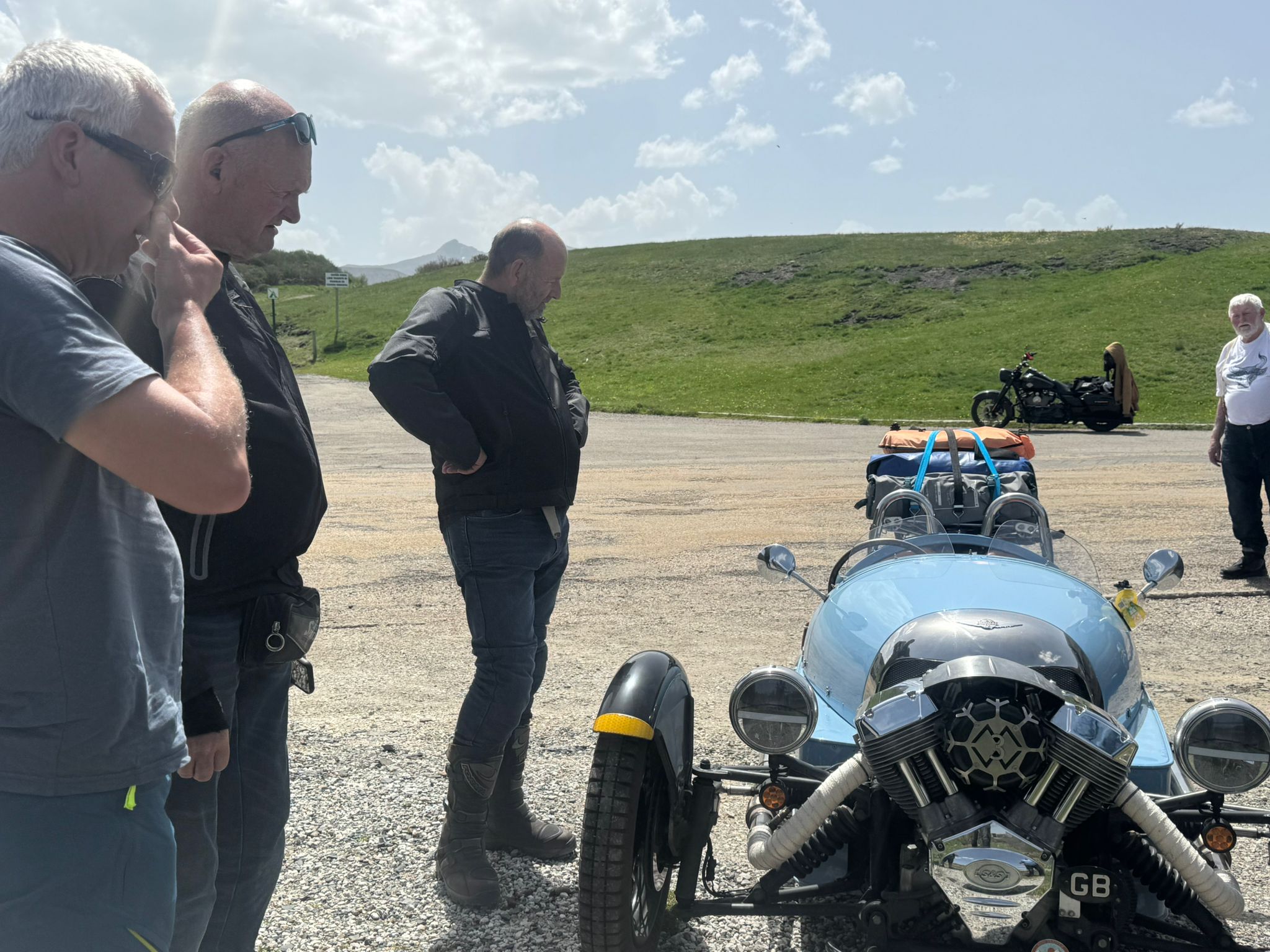 Wild Roads riders admiring a Morgan 3-wheeler at a Picos mountain stop