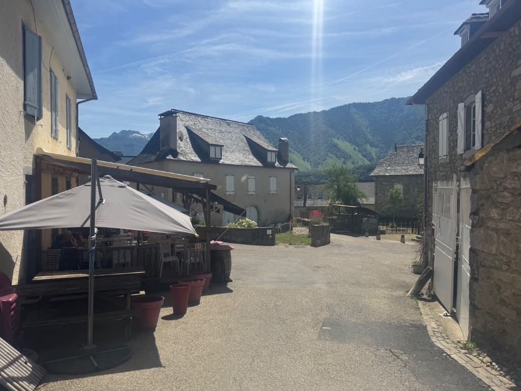Village square of Montory in the French Pyrenees — stone buildings and mountain backdrop — Wild Roads May 2026
