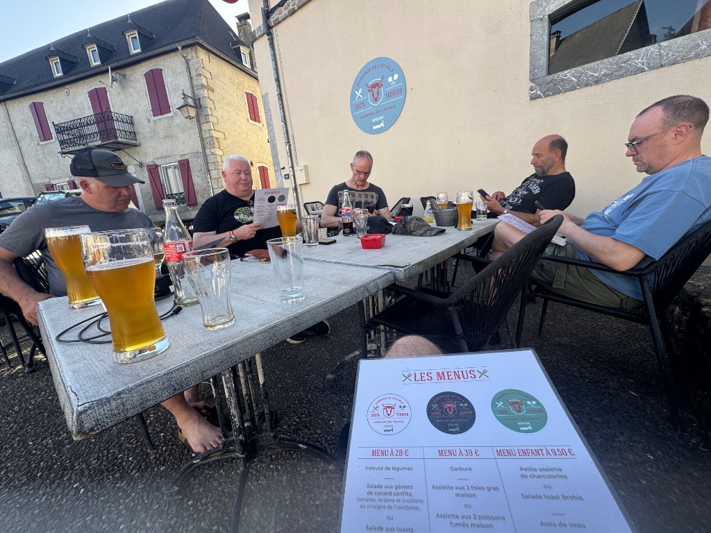 Wild Roads riders reviewing menus outside restaurant in Montory France — cold beers — Picos & Pyrenees May 2026