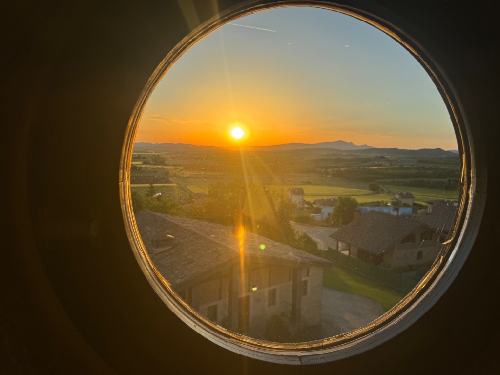 Sunset through porthole window at Parador de Argomaniz — Wild Roads Picos & Pyrenees May 2026