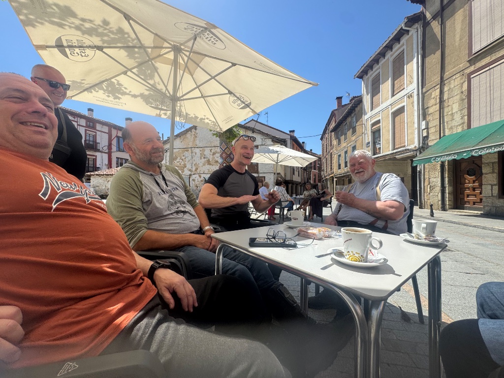 Wild Roads group laughing at café terrace in Cervera de Pisguera — Picos & Pyrenees Tour May 2026