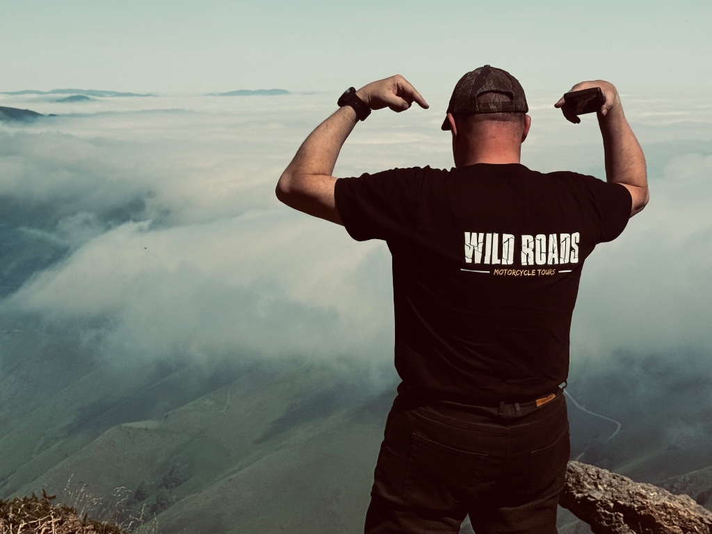 Wild Roads riders on coastal road approaching San Sebastián — Picos & Pyrenees May 2026