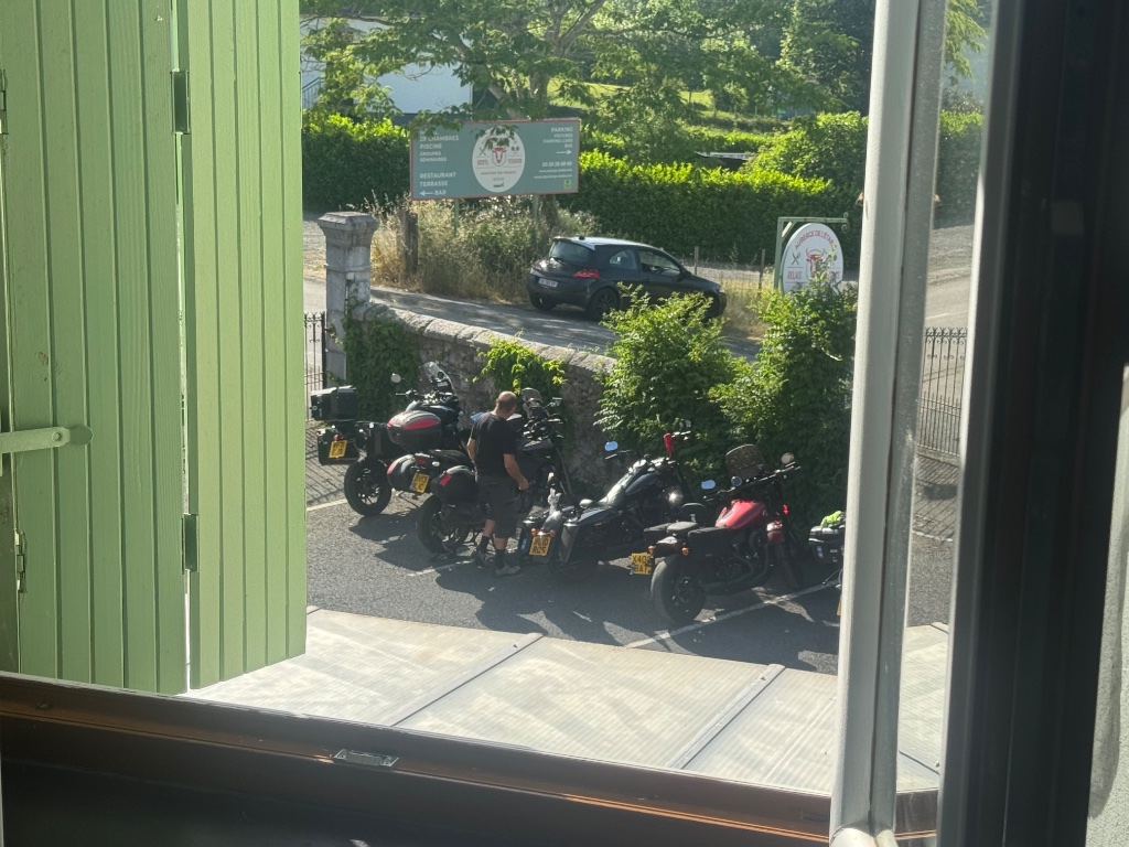 Wild Roads bikes parked outside Logis Hôtel l'Auberge de l'Etable hotel in Montory France — view from bedroom window — May 2026