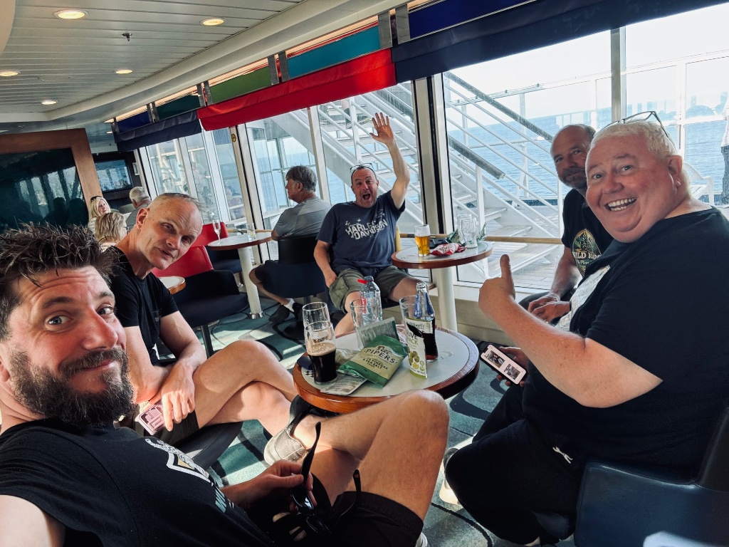 Wild Roads group celebrating on ferry bar end of tour — Picos & Pyrenees May 2026