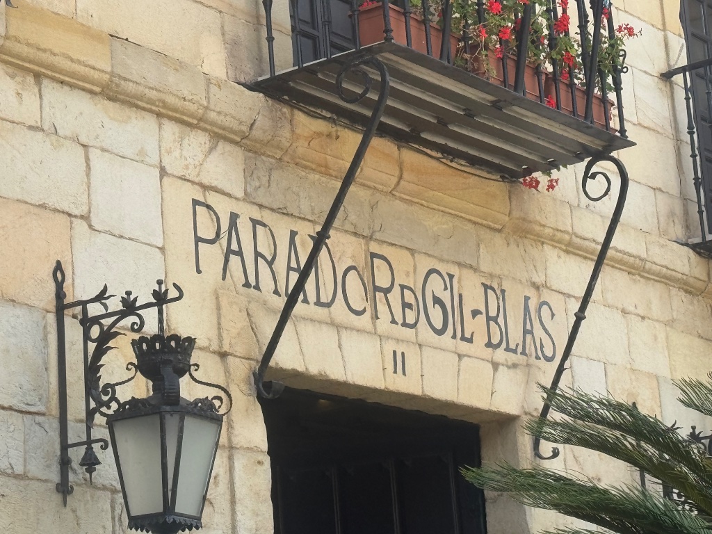 Parador de Gil Blas entrance sign stone arch iron lantern Santillana del Mar — Picos & Pyrenees May 2026