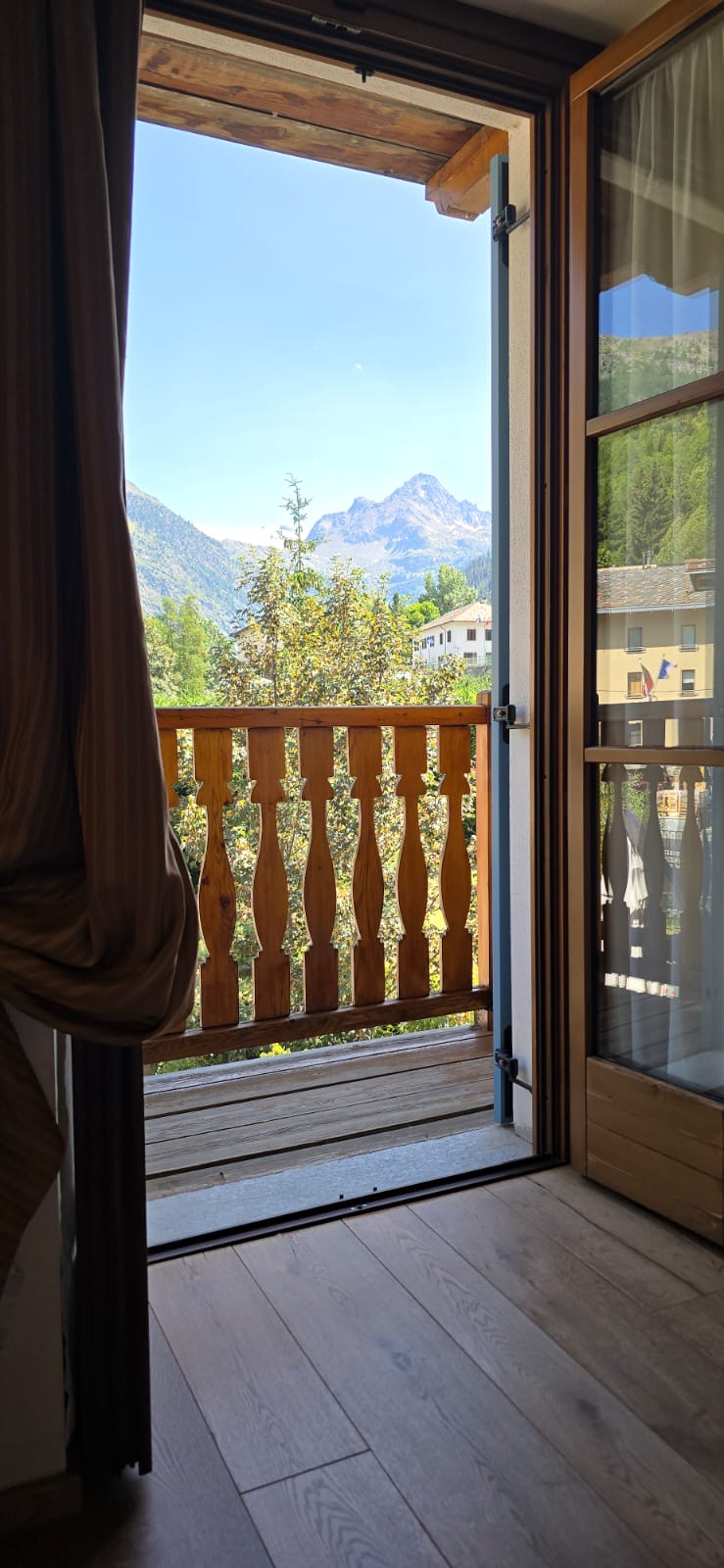Alpine river rushing through La Thuile surrounded by wooden chalets and mountain slopes